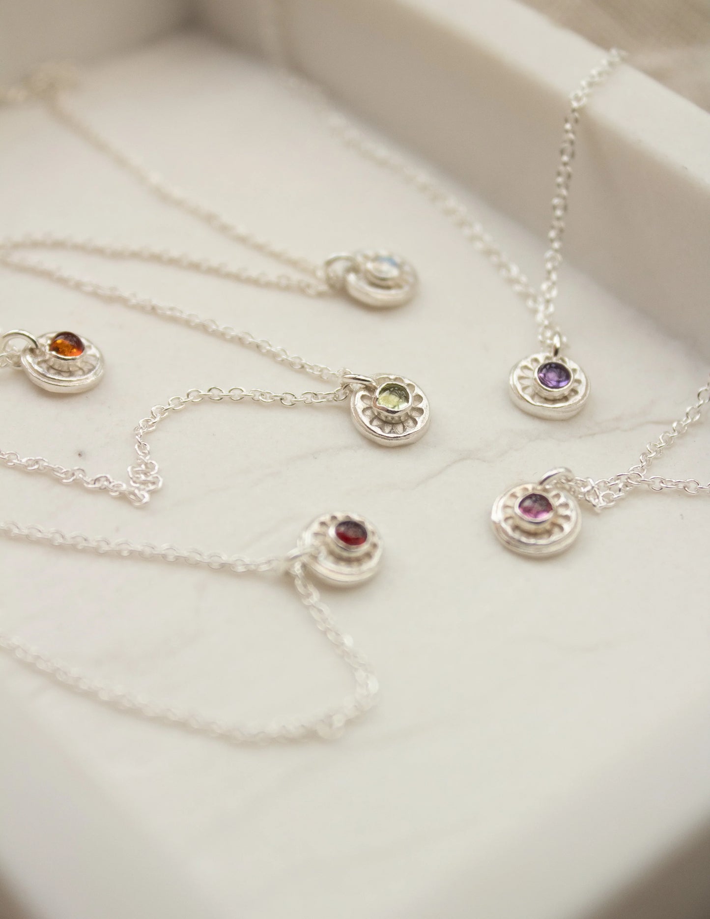 Sterling silver gemstone necklaces with round pendants in a jewelry box