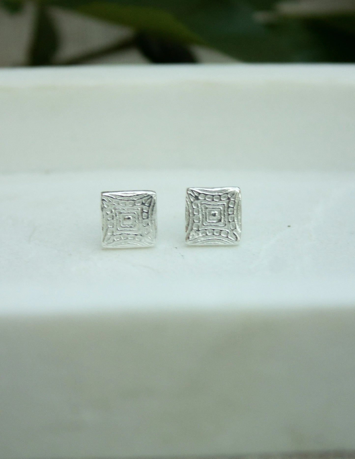Sterling silver square stud earrings with geometric textured pattern on white background