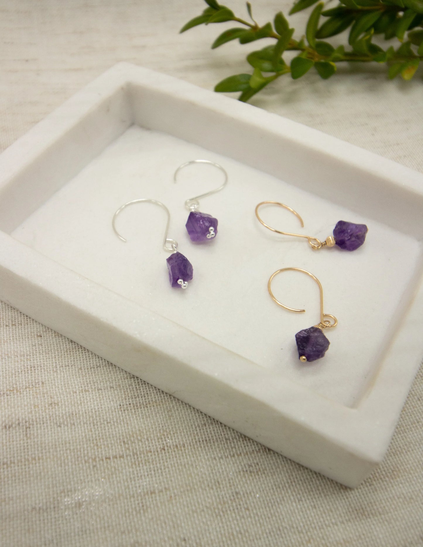 Handmade amethyst gemstone drop earrings in silver and gold on a white tray