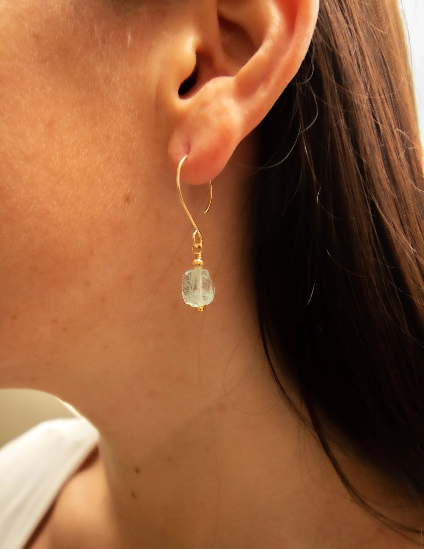 Gold filled earring with raw gemstone drop on woman's ear, handmade jewelry