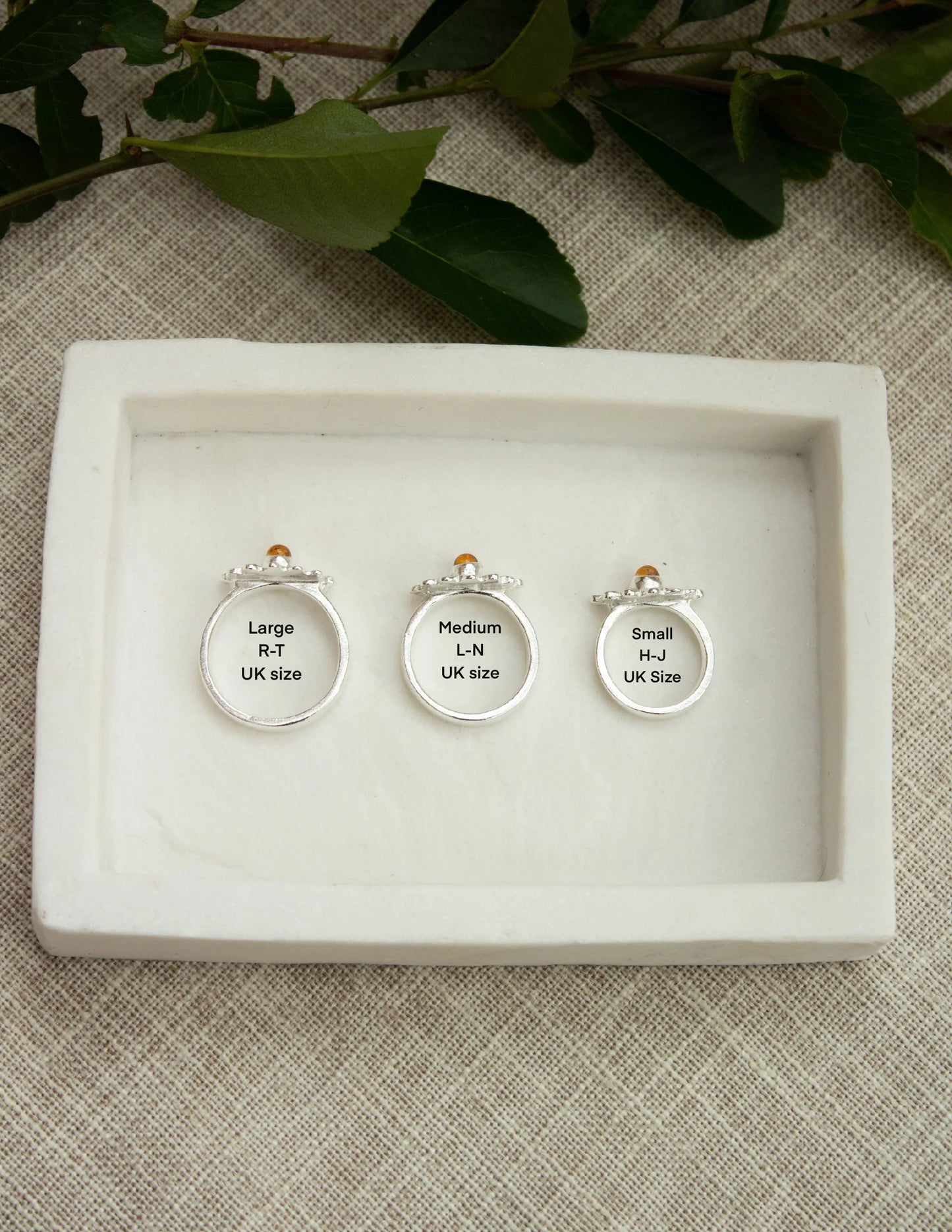 Three sterling silver gemstone rings in large, medium, and small UK sizes on a tray.