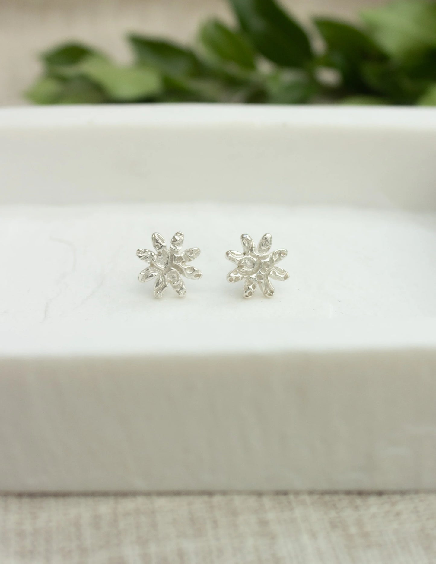 Sterling silver handmade floral stud earrings on a white jewelry tray