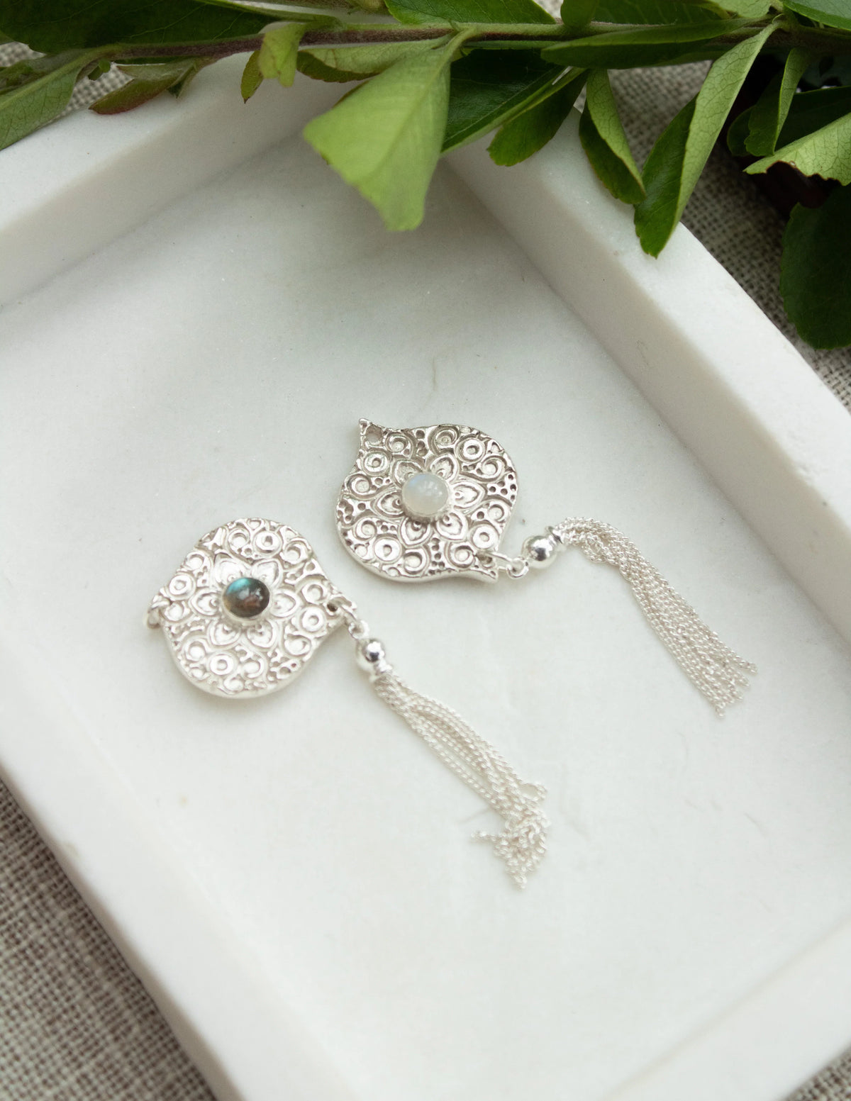Sterling silver filigree earrings with gemstone center and chain tassels on tray
